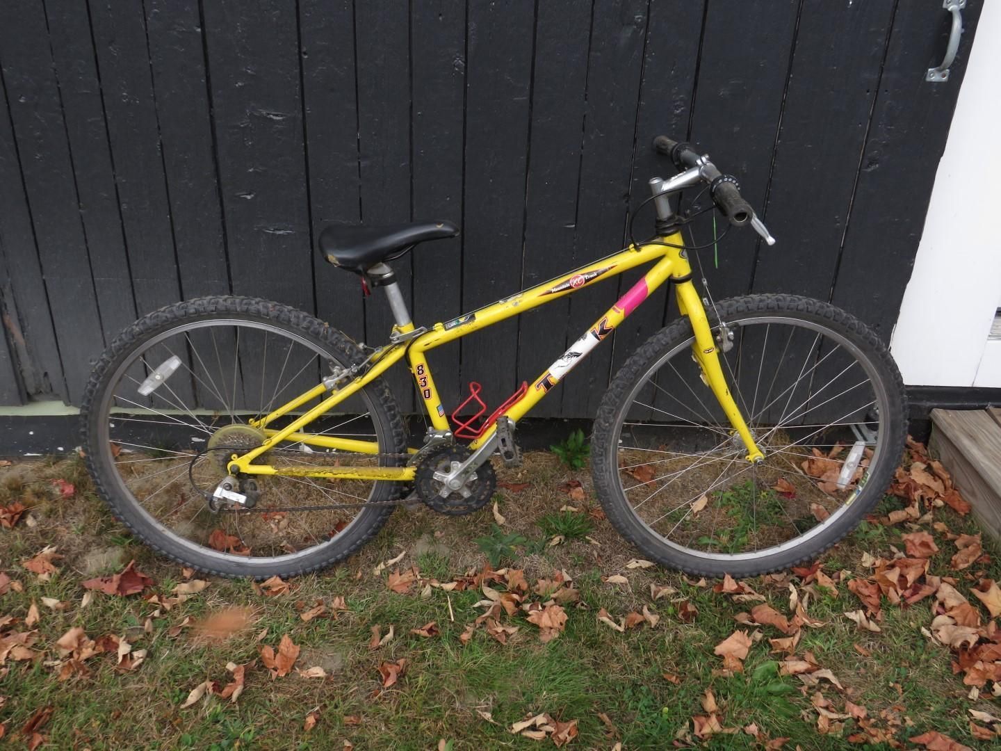 Yellow mountain bike against a dark wooden wall.