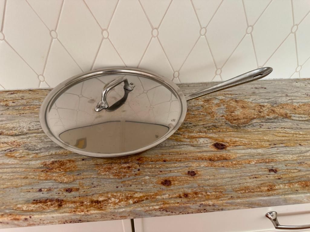 Stainless steel pan with lid on a granite countertop.