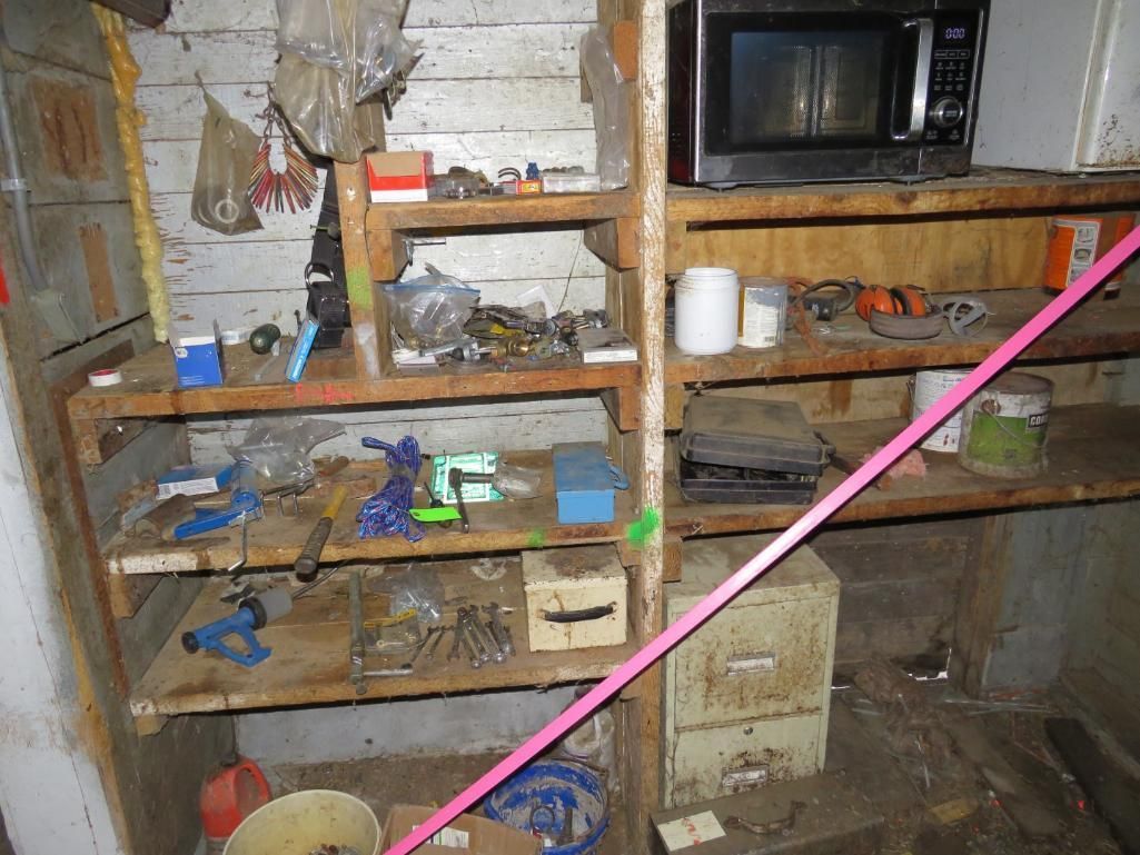 Wooden shelves in a workshop: tools, microwave, jars, and boxes.
