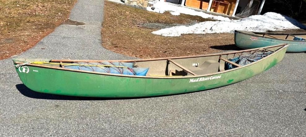 Green canoe on asphalt path. Another canoe in the background.