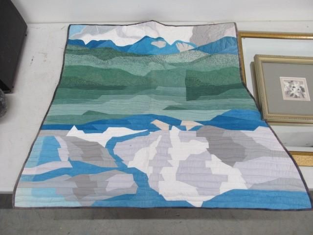Abstract landscape quilt in shades of blue, green, and gray depicting mountains and water.