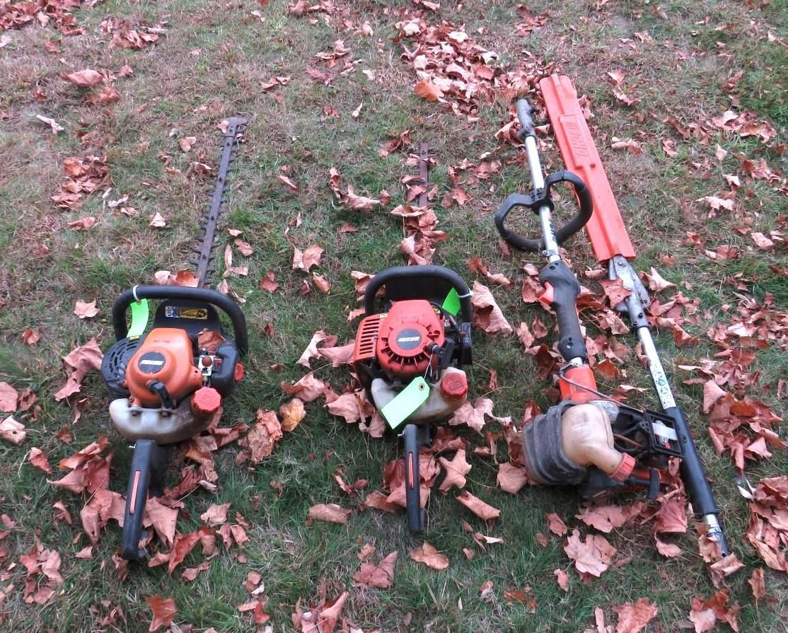 Three gas-powered landscaping tools: chainsaw, trimmer, and hedge trimmer.