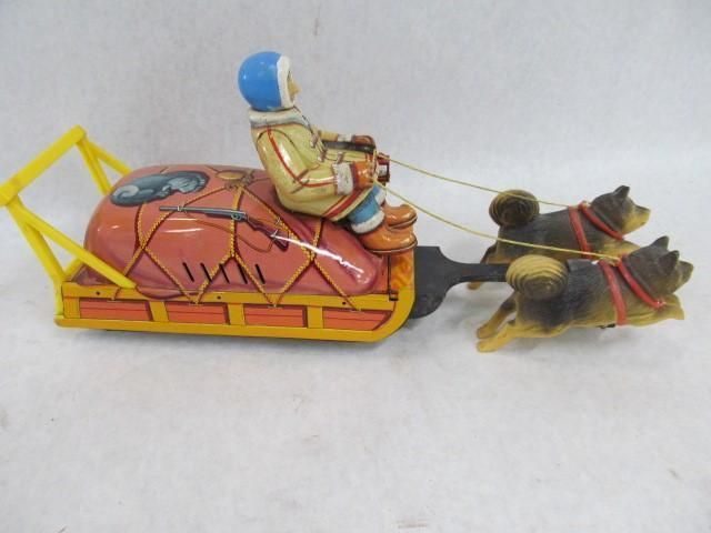 Toy dog sled with driver, pink cargo, yellow frame, and two dogs pulling.