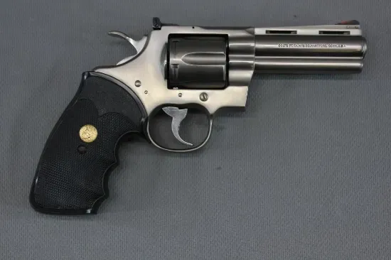 Silver revolver with black grip on a gray surface.