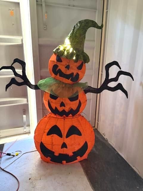 Stacked orange jack-o'-lantern decoration with black facial features, green hat and arms. Halloween Decoration.