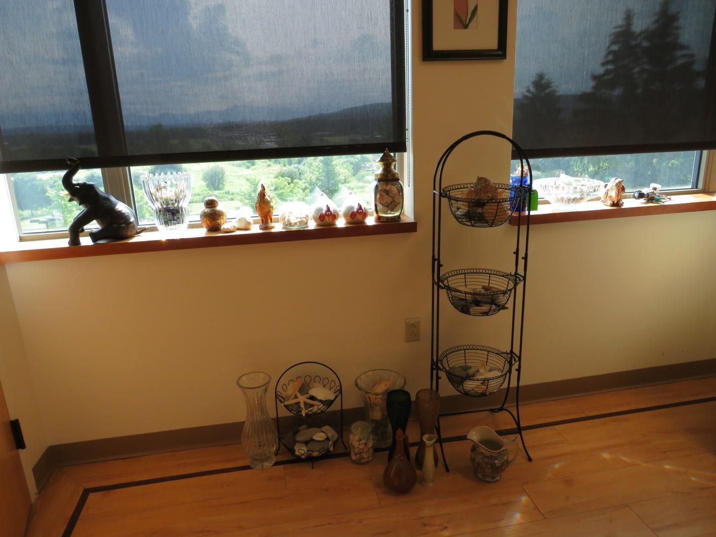 Room with windows, wooden floor, and decorative items on window sills and a metal rack.