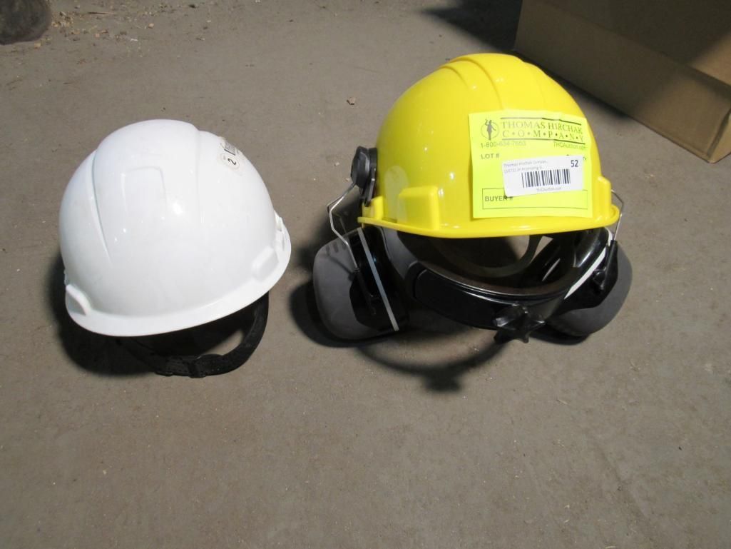 White and yellow hard hats, resting on a concrete floor.