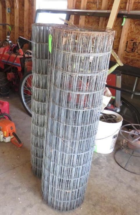 Two rolls of wire fence standing in a garage.