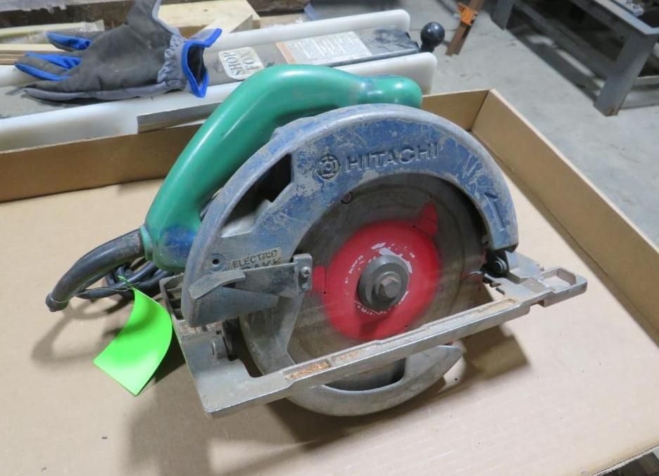 Blue and green Hitachi circular saw on a cardboard surface.