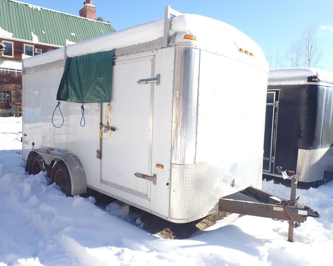 White enclosed trailer in snow; green tarp on side.