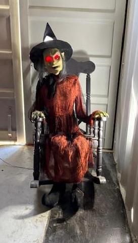 Animated witch prop sits in rocking chair with red glowing eyes. Halloween Decoration.
