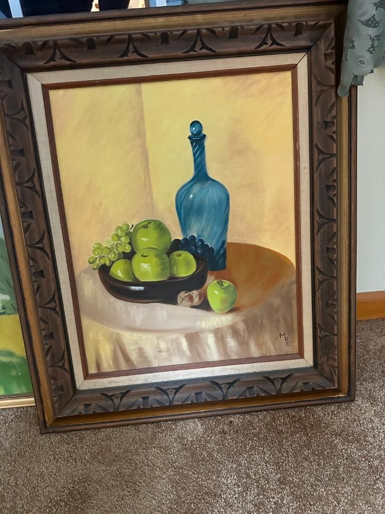 Still life painting of apples, grapes, and blue bottle on a table, with ornate brown frame.