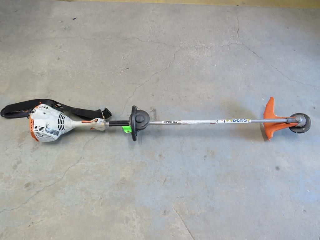 String trimmer on a concrete surface with orange guard.