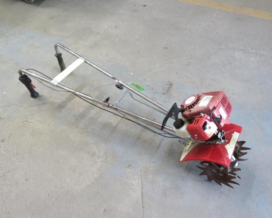Red and silver Honda tiller on a concrete surface.