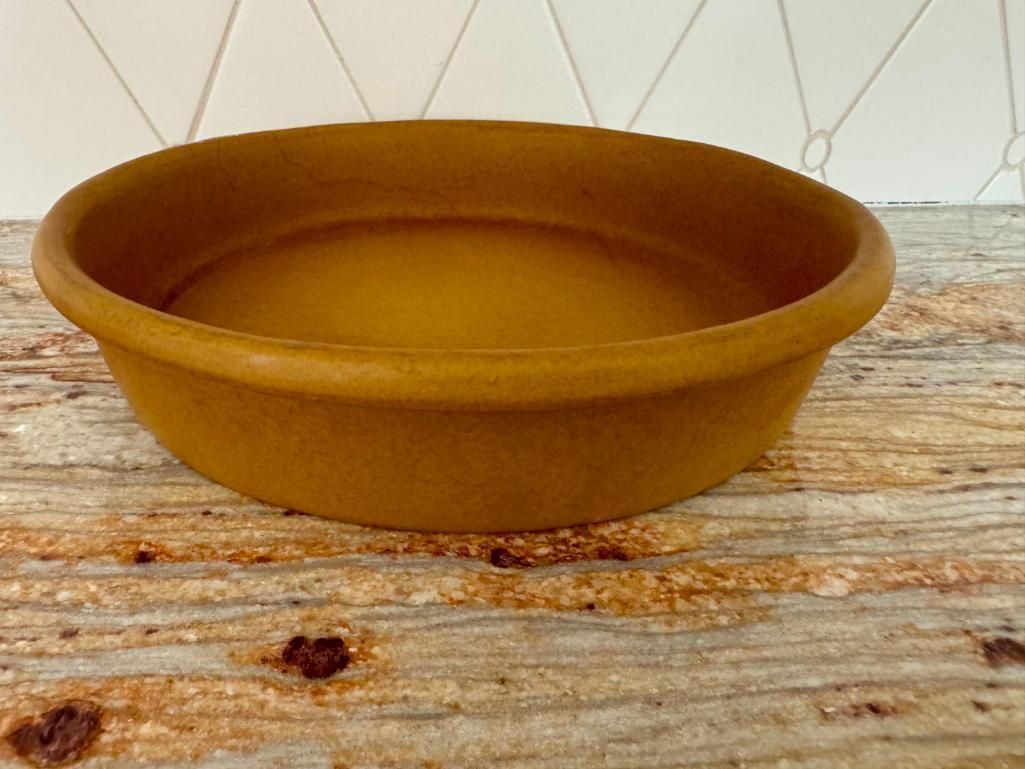 Brown, round terracotta bowl on a granite countertop.