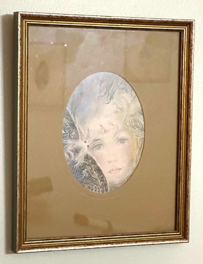 Oval portrait of a person with a soft gaze, framed with gold trim on a neutral background.