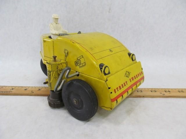 Yellow toy road roller with black wheels and a white driver.