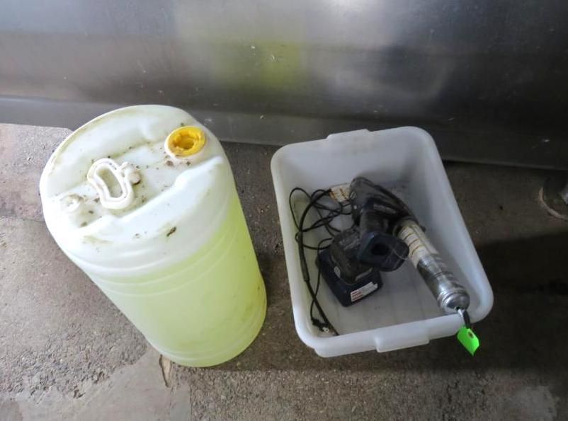 White plastic jug of yellow liquid and a tray with a tool and charger.