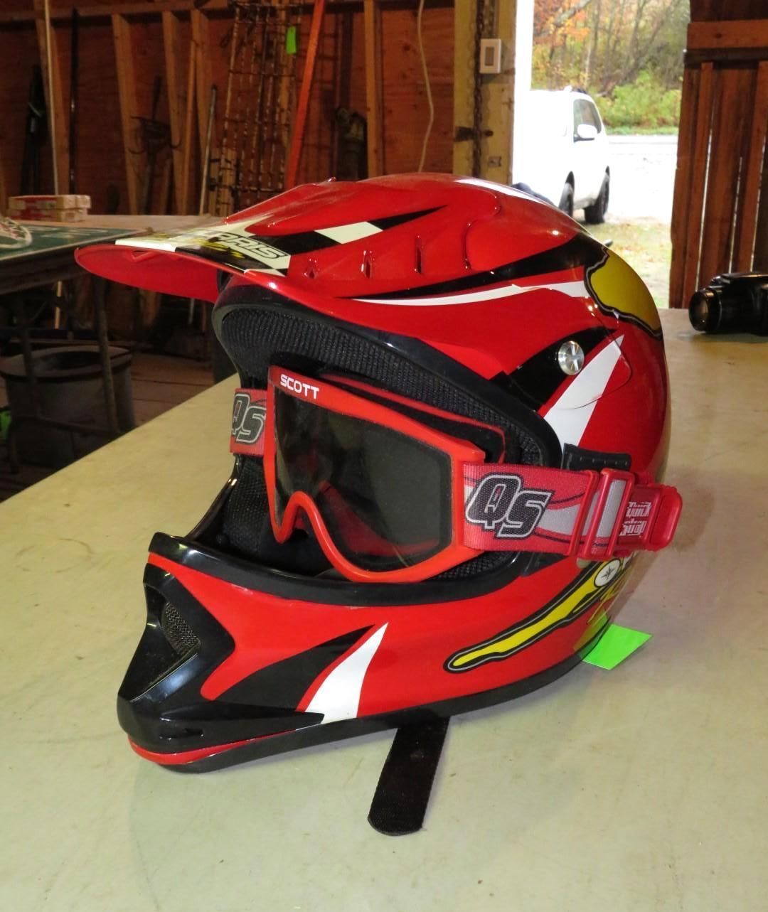 Red and black motocross helmet with matching goggles, on a table.