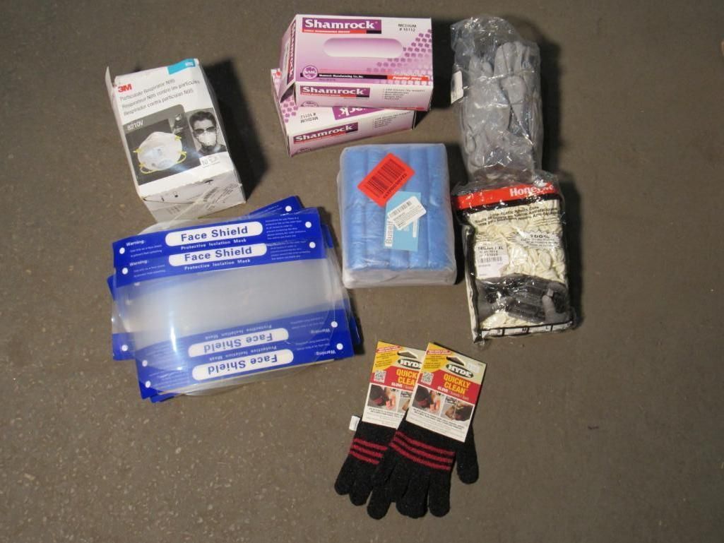 Various personal protective equipment (PPE) on a dark surface including face shields, gloves, masks, and gloves.