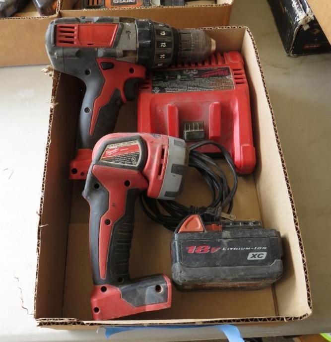 Box with red and black Milwaukee power tools: drill, work light, charger, and battery.