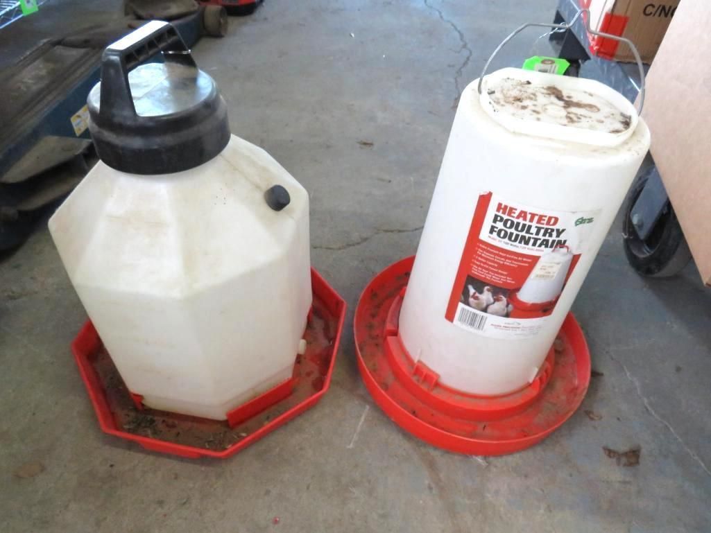 Two white plastic chicken waterers with red bases on a concrete floor.