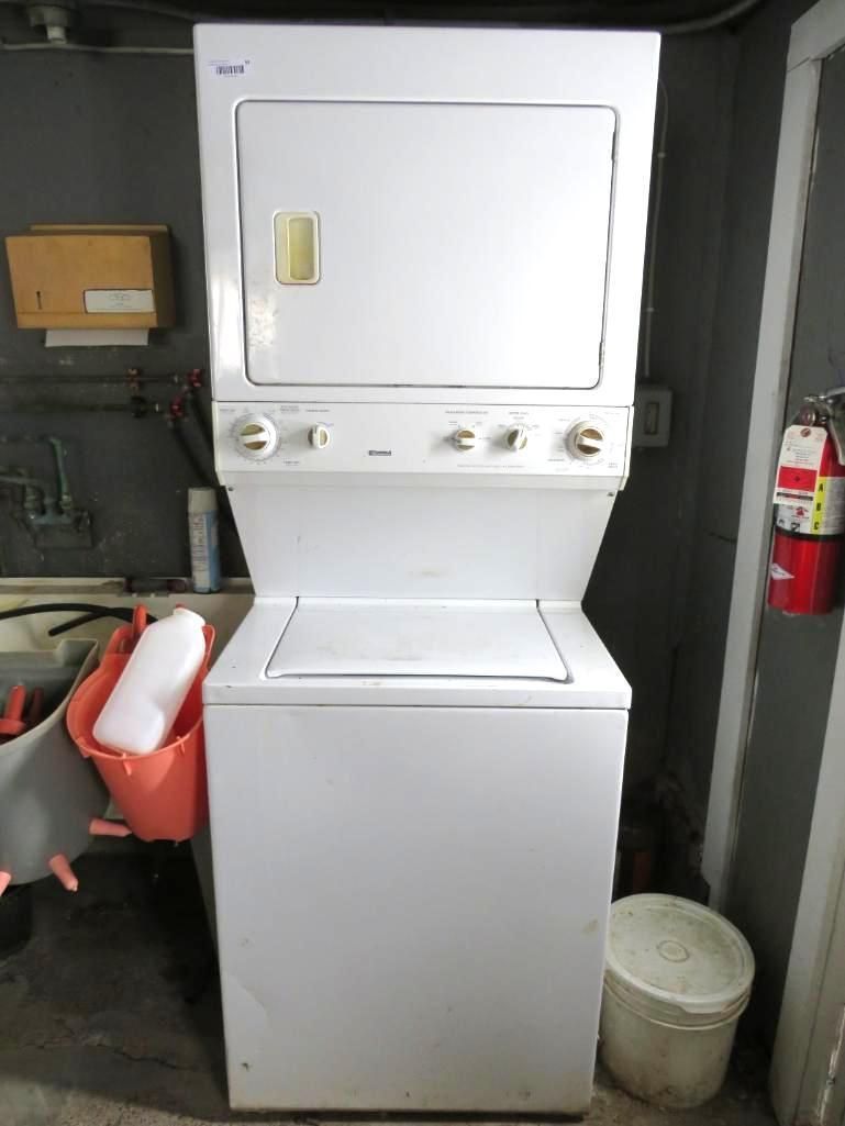 White stacked washer and dryer in a utility room. Controls on front panel.