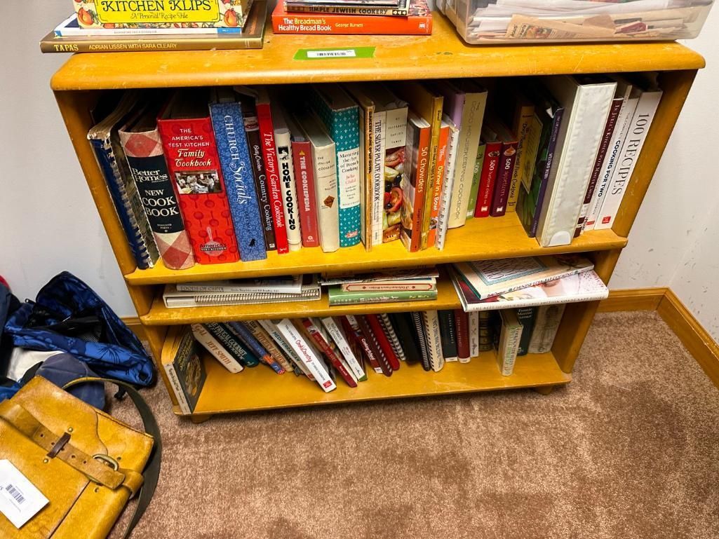 Wooden bookshelf with books on shelves, some books on top.