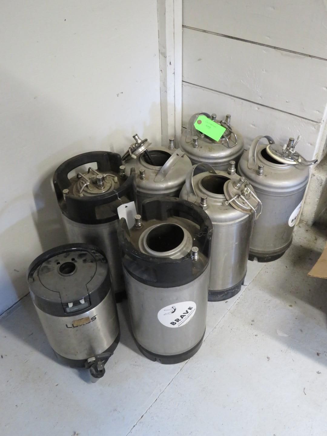 Group of stainless steel kegs in a corner, some with lids open.