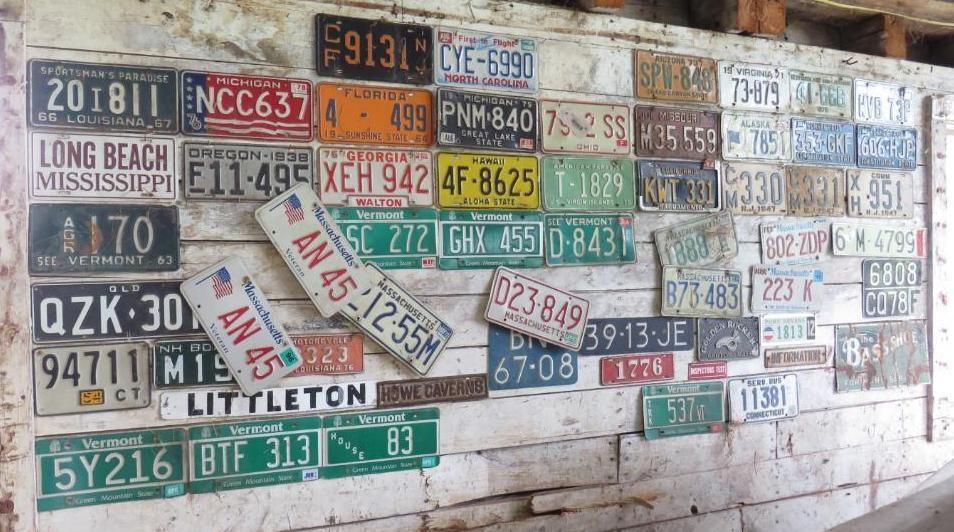 Collection of assorted license plates mounted on a wooden wall.