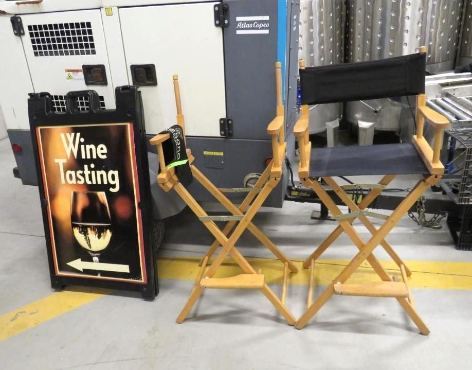 Wine tasting sign next to two wooden director's chairs.
