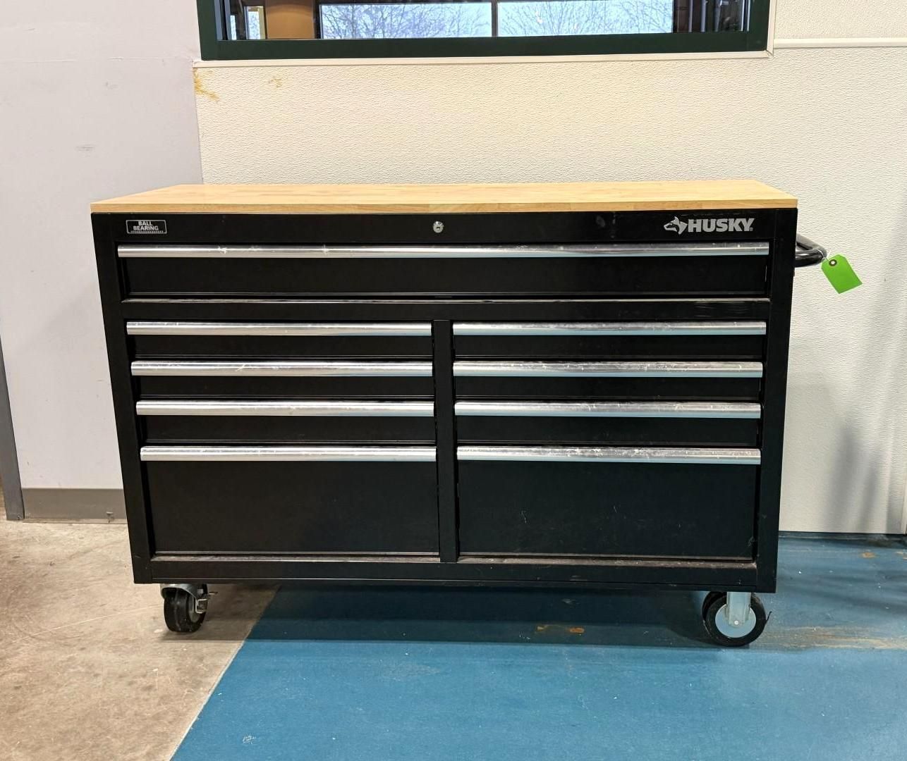 Black Husky tool cabinet with wooden top and multiple drawers on wheels.