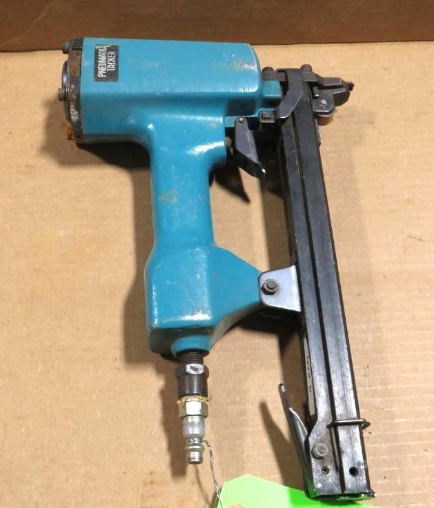 Blue pneumatic finish nailer on a brown surface.