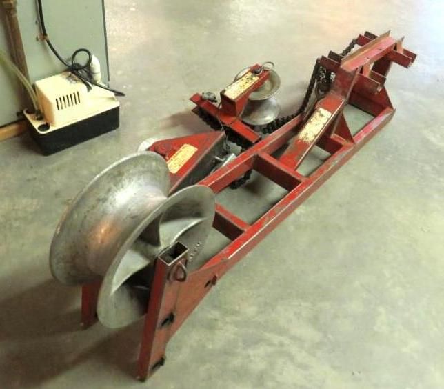 Red cable pulling machine with large spools, indoors on a concrete floor.