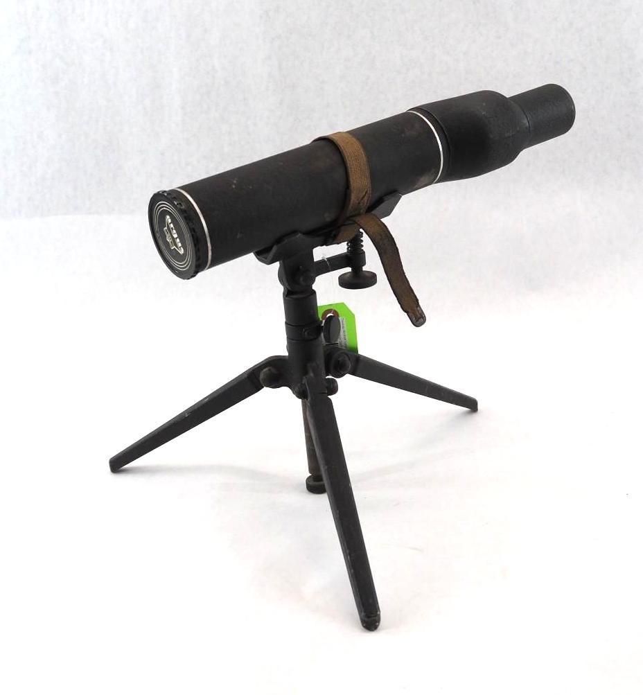 Black telescope on a small tripod, angled upward with a brown strap attached