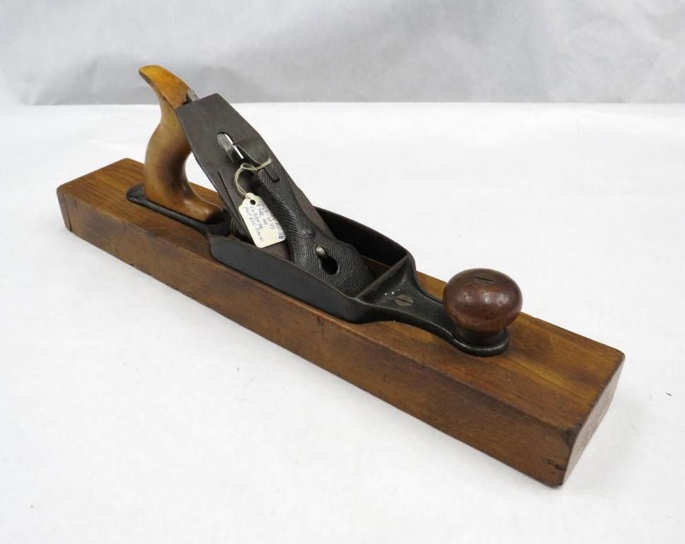 Wooden hand plane with a dark metal blade and handles on a white background.
