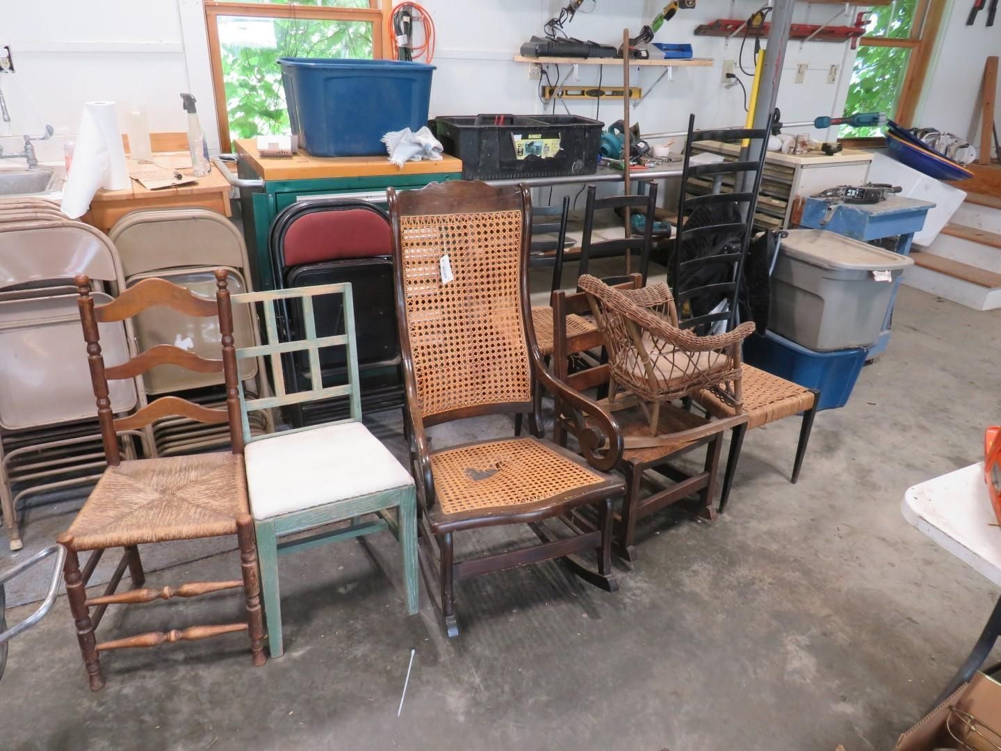 Various chairs of different styles on a garage floor.