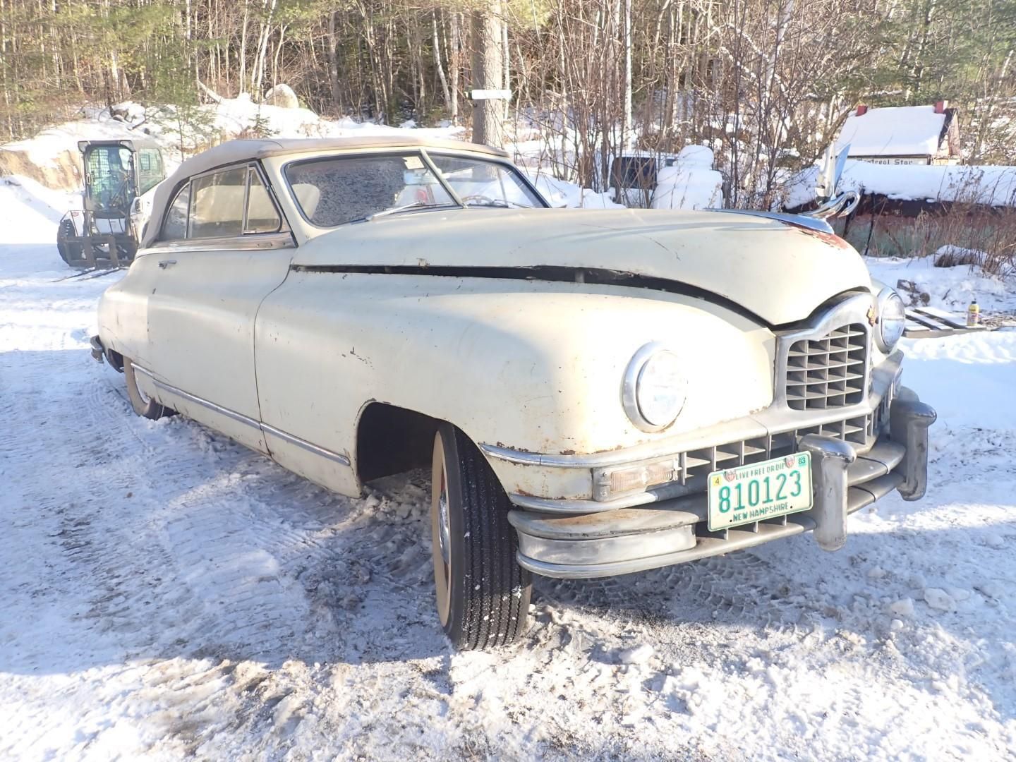 Cream-colored classic Packard Convertible car parked in snow.
