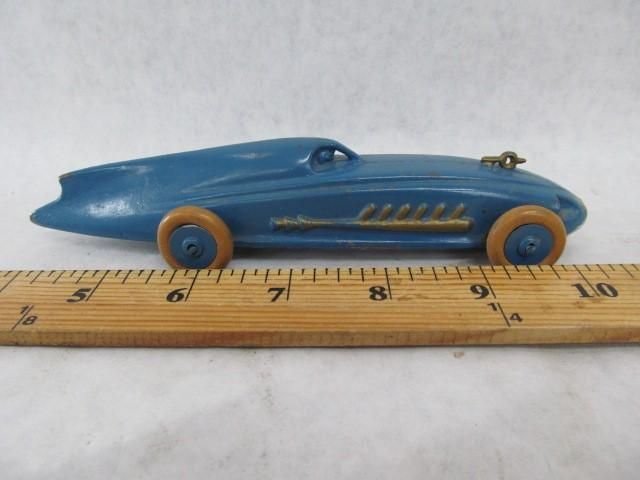 Blue toy race car with wooden wheels, next to a ruler.