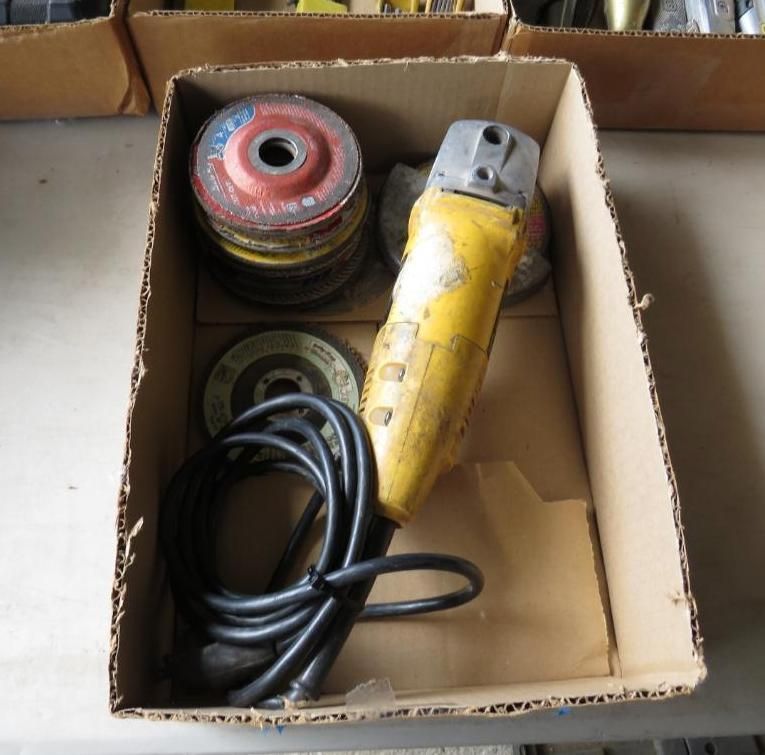Yellow angle grinder, several discs, and black cord in cardboard box.