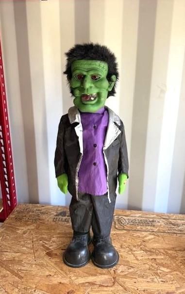 Green-skinned monster doll in a purple shirt and black suit, smiling. Halloween Decoration.