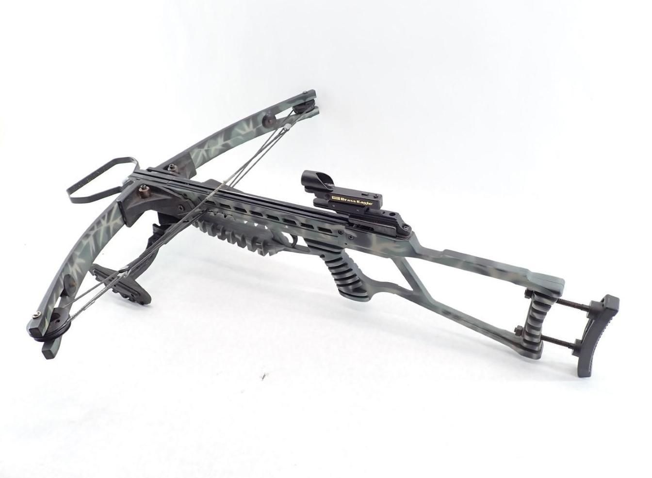 Camouflaged crossbow on a white background, featuring a scope and a textured grip.