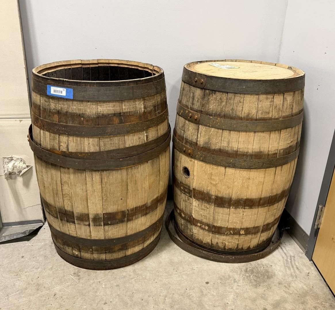 Two wooden barrels with metal bands, one empty, the other with a top.