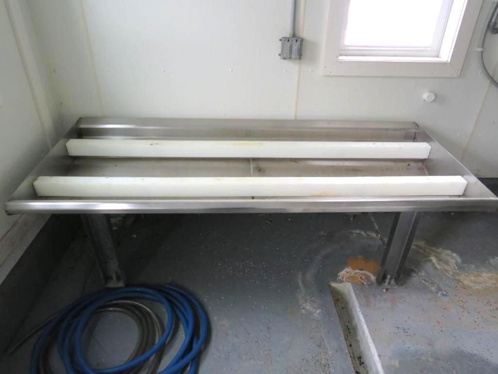 Stainless steel work table with two white rollers.