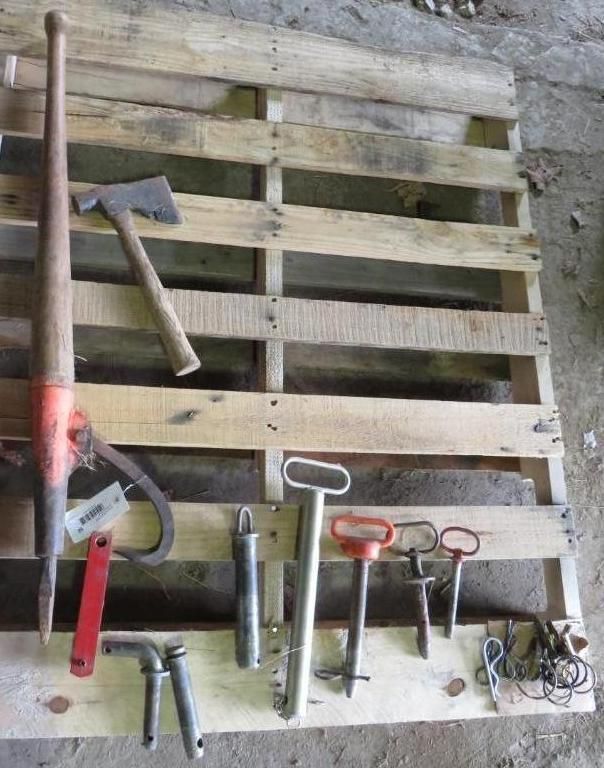 Tools, including an ax, pliers, and various metal keys, arranged on a wooden pallet.