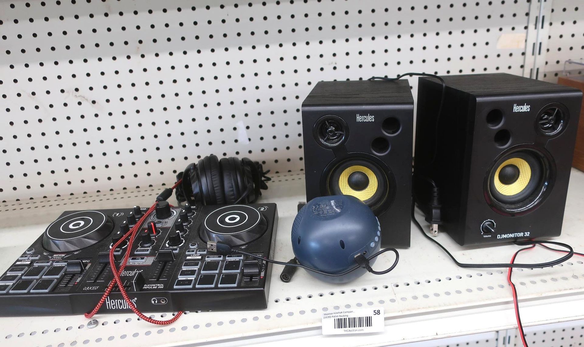 DJ equipment: controller, headphones, speakers, and a blue Bluetooth speaker on a shelf.