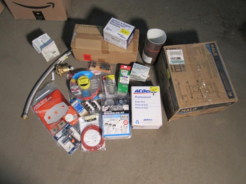 Pile of plumbing and hardware supplies on a floor. Includes boxes, pipes, and various components.