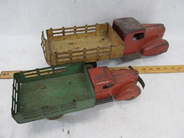 Two vintage metal toy trucks, red and green, with open beds.