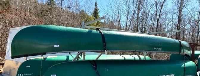 Green canoes stacked on top of each other, held in place with black straps.