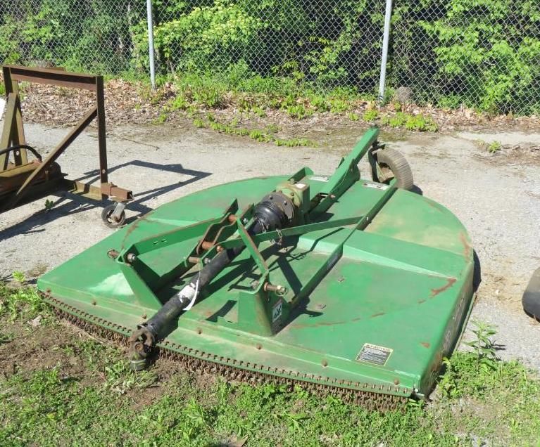 Green rotary mower, likely for tractor use, on grassy ground.